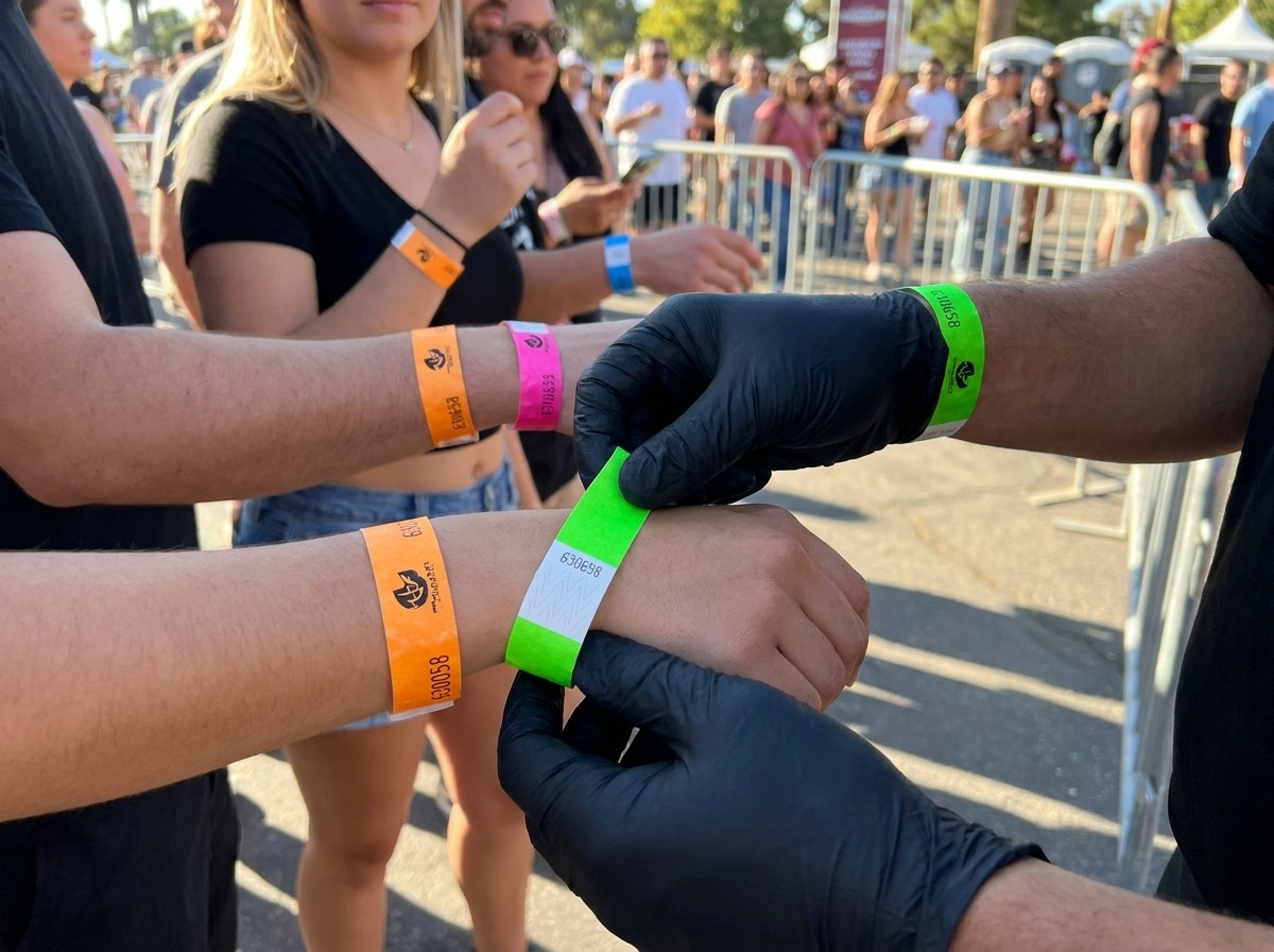 Ordningsvakt som kontrollerar färgglada armband vid evenemangets inpasseringspunkt
