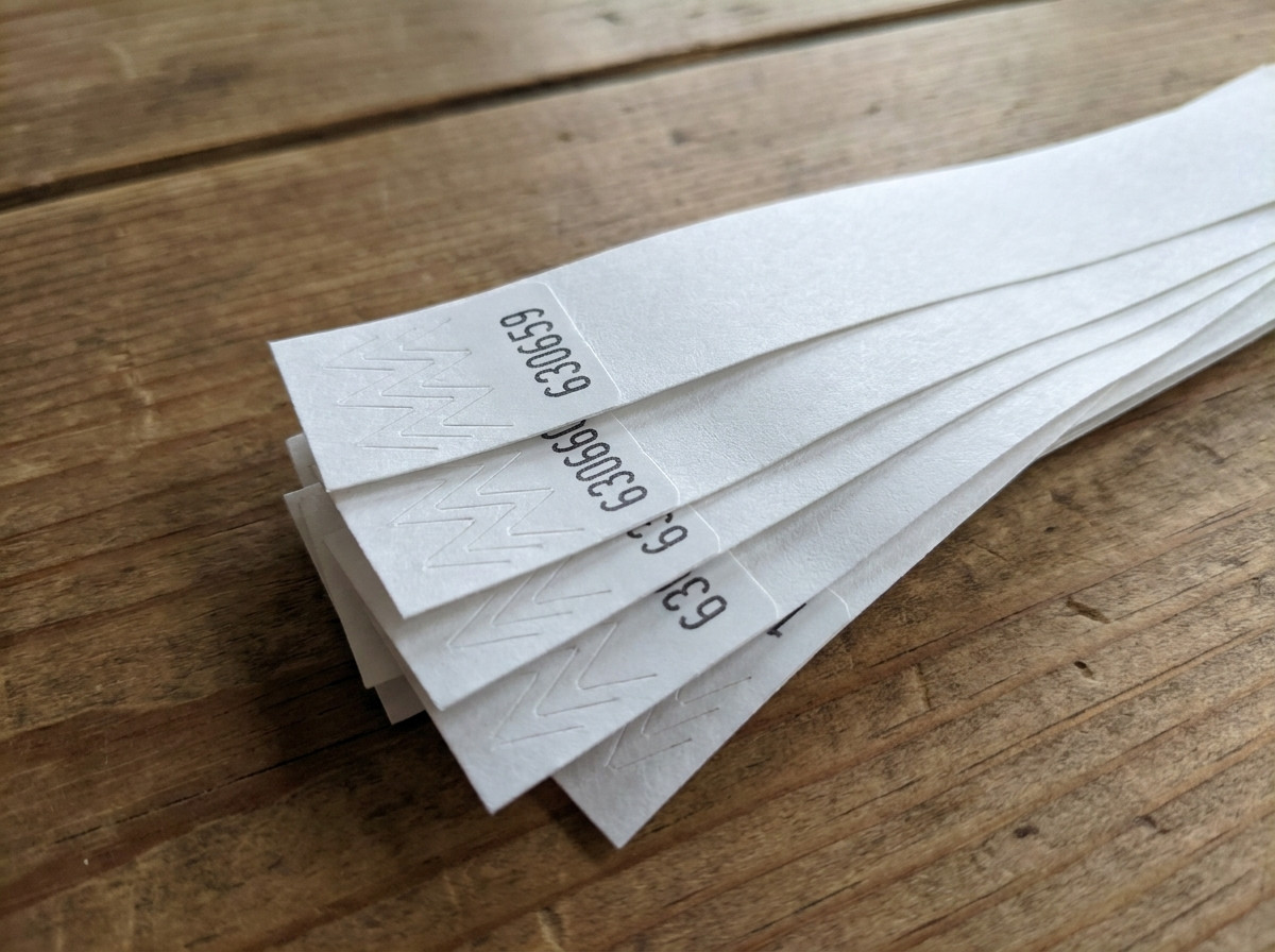 Närbild på Tyvek-armband med sekventiell numrering tryckt i svart, arrangerade som en solfjäder på ett accesskontrollbord vid ett evenemang