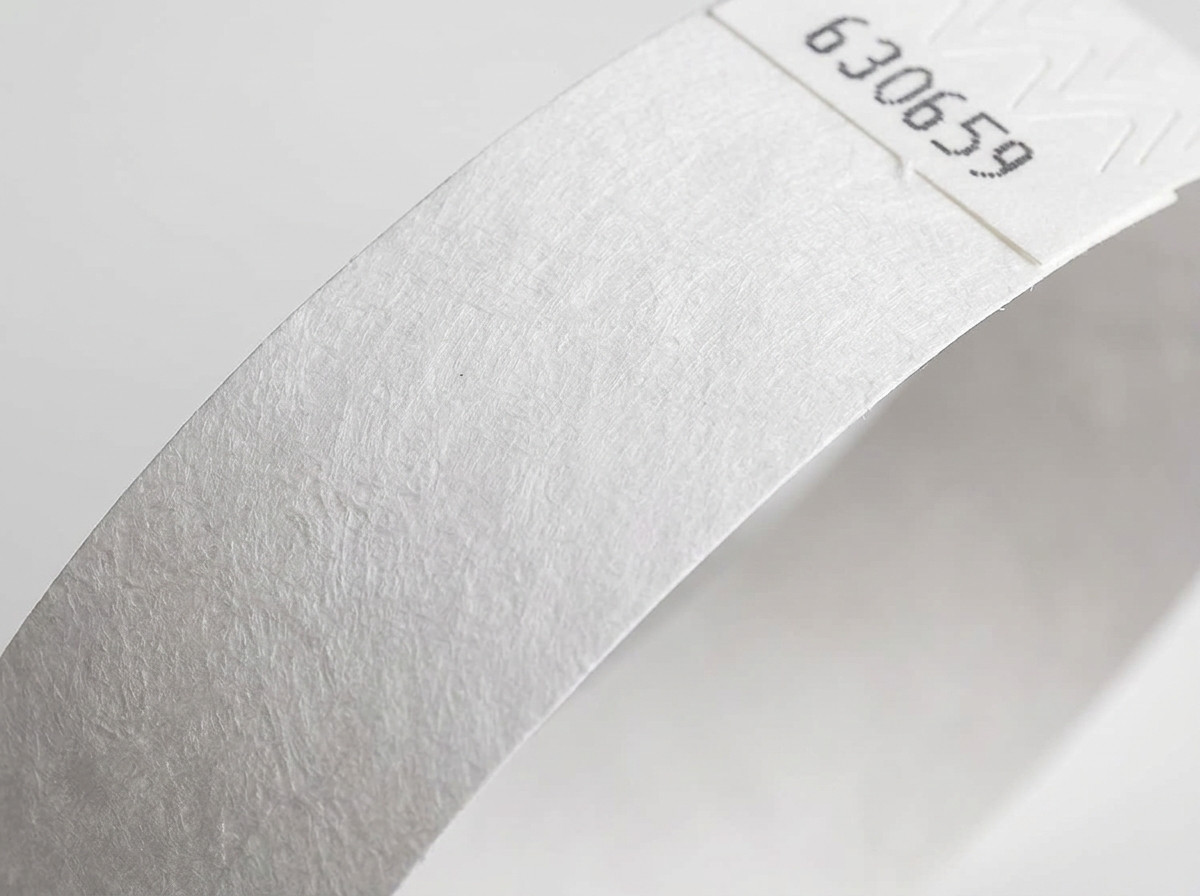 Närbild på den icke-vävda ytan hos ett vitt Tyvek-armbånd som visar den karaktäristiska texturen hos högdensitetspolyeten